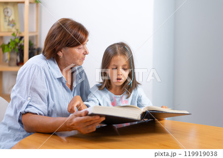 Grandmother and granddaughter reading book 119919038