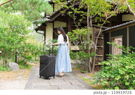 キャリーケースを引いて田舎に帰省する若い女性　旅行イメージ  119919728