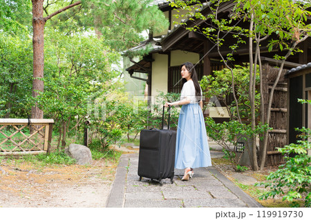 キャリーケースを引いて田舎に帰省する若い女性　旅行イメージ  119919730