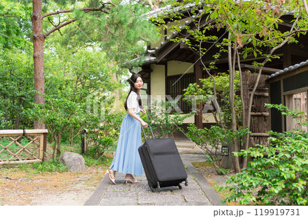 キャリーケースを引いて田舎に帰省する若い女性 旅行イメージ キャリーケースを引いて田舎に帰省する若い女性 旅行イメージ 119919731