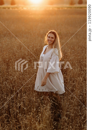 A woman is standing in a field of tall grass A woman is standing in a field of tall grass 119920090