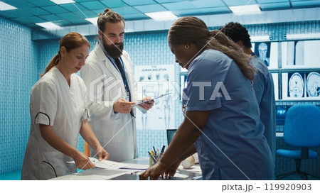 Healthcare team discusses human anatomy and diagnostic strategies in a medical office. Collective work ensures accurate treatment plans and professional solutions, expertise in radiology. Camera B. 119920903