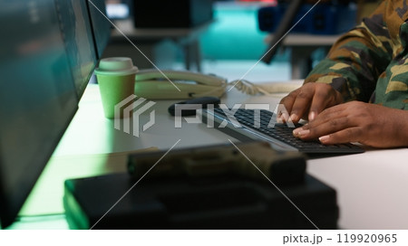 Military officer making telephone call to relay enemy info gained using tracking equipment. Army specialist talking on phone, giving intel helping troops, coordinating mission activities, camera A 119920965