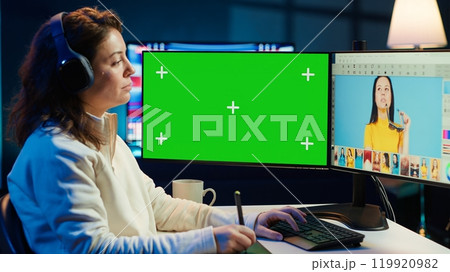 Photo editor using green screen monitor to color correct photographs in creative studio, listening music. Photographer selecting best pictures for editorial content with chroma key computer, camera A Photo editor using green screen monitor to color correct photographs in creative studio, listening music. Photographer selecting best pictures for editorial content with chroma key computer, camera A 119920982