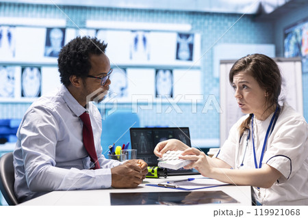 Physician recommending vitamins and painkillers on healthcare insurance, writing a prescription document with instructions and the right dosage of medication. Modern healthcare services. 119921068