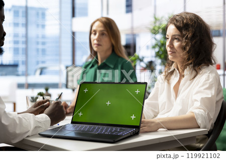 Employers conducts interview with jobseeker using green screen laptop to determine suitability for company position. HR colleagues reviewing resume on mockup notebook to see if qualifications are met Employers conducts interview with jobseeker using green screen laptop to determine suitability for company position. HR colleagues reviewing resume on mockup notebook to see if qualifications are met 119921102