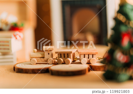 クリスマスの木製ミニチュアトレインと暖炉のある温かなシーン クリスマスの木製ミニチュアトレインと暖炉のある温かなシーン 119921803