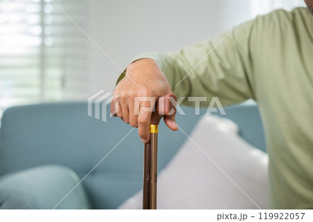 Asian Old man with eyeglasses typing to stand up from sofa with walking cane, Elderly suffering from knee pain ache holding handle of cane, senior disabled man holding walking stick at home Asian Old man with eyeglasses typing to stand up from sofa with walking cane, Elderly suffering from knee pain ache holding handle of cane, senior disabled man holding walking stick at home 119922057