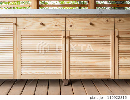 Wooden outdoor kitchen cabinets with louvered doors and a marble top 119922816