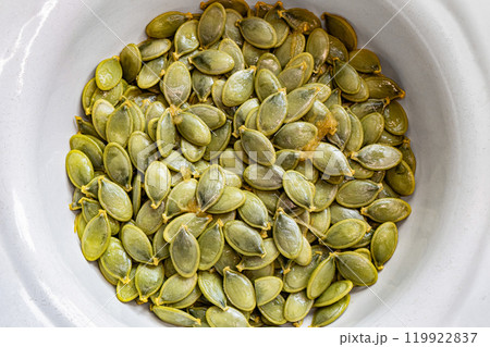 Fresh pumpkin seeds in a white bowl curved at the edges Fresh pumpkin seeds in a white bowl curved at the edges 119922837