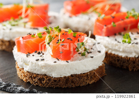 Healthy rye bread sandwich with red fish, cream cheese, sesame and microgreens close-up on slate plate. Horizontal Healthy rye bread sandwich with red fish, cream cheese, sesame and microgreens close-up on slate plate. Horizontal 119922861