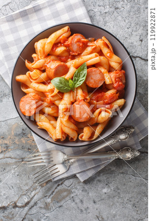 Treccione pasta with tomato, onion, sausage and spices close-up in a bowl. Vertical top view Treccione pasta with tomato, onion, sausage and spices close-up in a bowl. Vertical top view 119922871