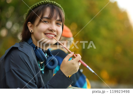 Creative Spirit. The Young Artist in Nature. a young female artist passionately painting outdoors, with brushes and paints in her hands. Surrounded by the beauty of nature, she is fully immersed in Creative Spirit. The Young Artist in Nature. a young female artist passionately painting outdoors, with brushes and paints in her hands. Surrounded by the beauty of nature, she is fully immersed in 119923498