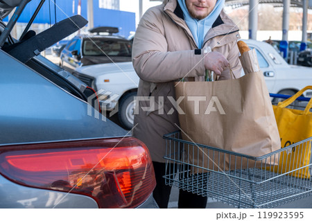 Man Loading Groceries into Car Trunk Man Loading Groceries into Car Trunk 119923595