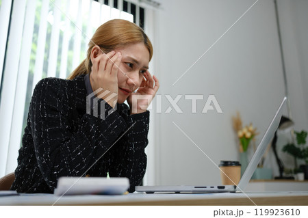 A woman is sitting at a desk with a laptop and a cup of coffee 119923610