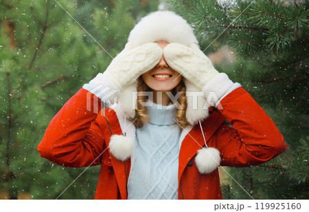 Winter portrait of happy smiling woman having fun enjoys snow against Christmas tree in forest 119925160