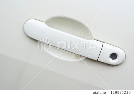 White car handle with lock, key hole after rain 119925239