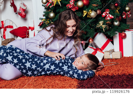 Mother and son at the Christmas tree with gifts for the new year 119926176