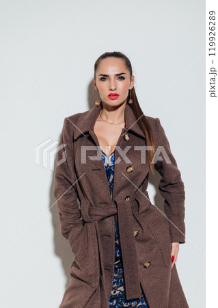 Beautiful fashionable woman in autumn beige coat on gray background Beautiful fashionable woman in autumn beige coat on gray background 119926289