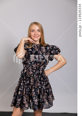 Beautiful fashion blonde woman in dress smiling on gray background Beautiful fashion blonde woman in dress smiling on gray background 119926334