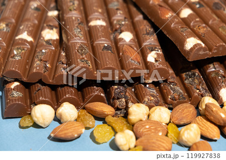Lots of chocolate bars with nuts and raisins on a blue background Lots of chocolate bars with nuts and raisins on a blue background 119927838