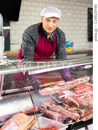Adult man puts beef ribs in showcase 119928498