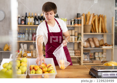Young male seller puts apples in bag 119928499