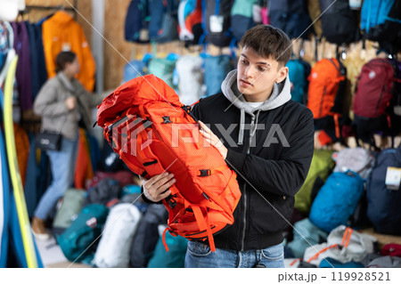 Buyer guy chooses winter backpack in store for hikes Buyer guy chooses winter backpack in store for hikes 119928521