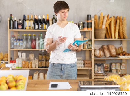 Man seller manager in shop make calculations, work with paper documents and count using phone 119928530
