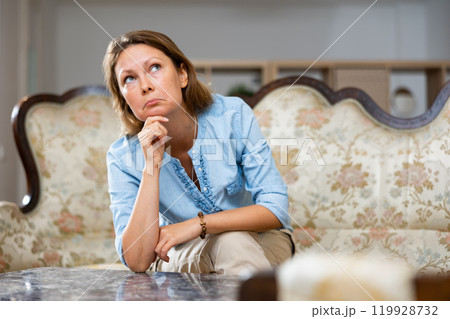 Sad woman sitting on sofa at home 119928732