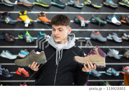 Guy examine view item of autumn comfortable trecking shoes Guy examine view item of autumn comfortable trecking shoes 119928801