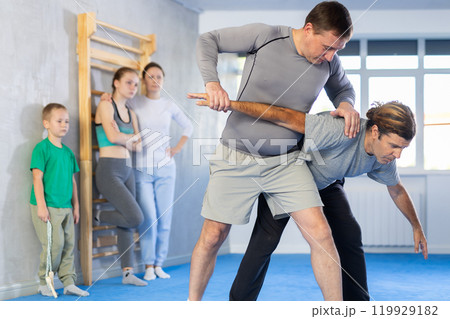Trainer and man are training in gym practicing hand grab technique Trainer and man are training in gym practicing hand grab technique 119929182