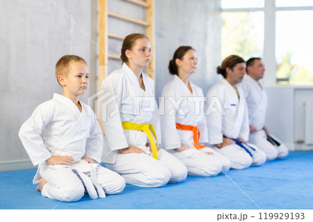 Group of people in kimono with master in sitting position during group karate training 119929193