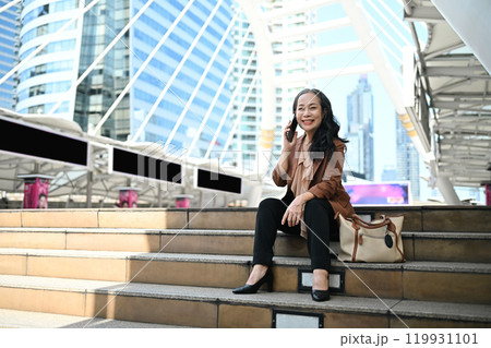 Confident mature businesswoman enjoying a phone conversation in modern city Confident mature businesswoman enjoying a phone conversation in modern city 119931101