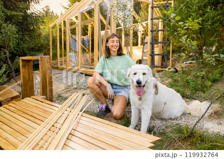 Female carpenter with her dog building wooden greenhouse 119932764