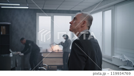Office robbery case: Medium close up of male detective examining crime scene Office robbery case: Medium close up of male detective examining crime scene 119934769
