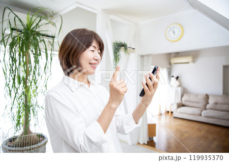 スマホ操作する女性、日本人ミドル　自宅のリビング 119935370