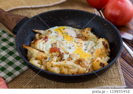 fried omelette with cauliflower and vegetables in a frying pan on a wooden table 119935458
