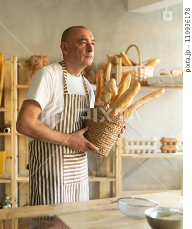 Man with basket of baguettes in bakery Man with basket of baguettes in bakery 119936178