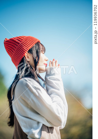 青空のもと遠くを見つめる若い女性 119936702