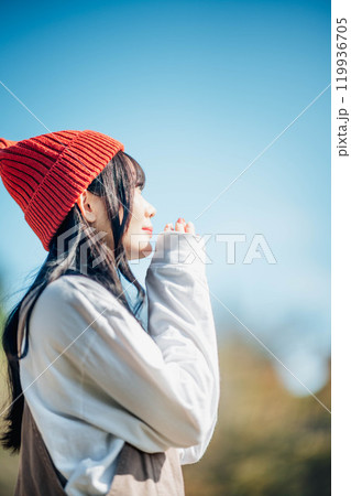 青空のもと遠くを見つめる若い女性 119936705