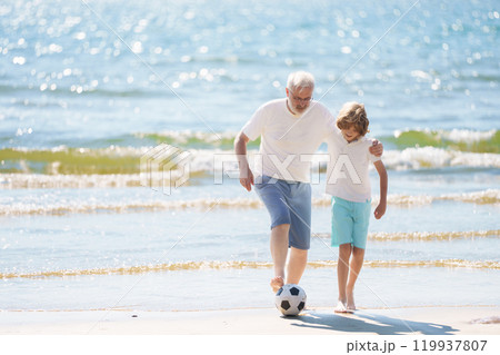 Grandfather and kids play football on beach. Grandfather and kids play football on beach. 119937807