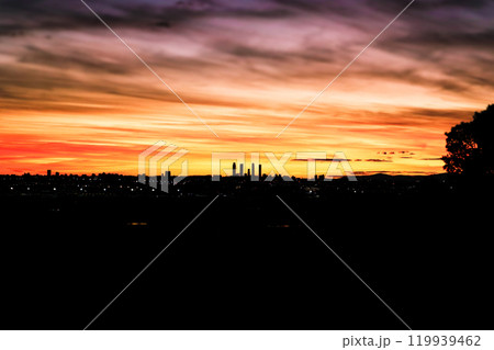 Fantastic sunset sky. Beautiful view of a night city Cuatro Torres business center, four office skyscrapers on a horizon, the tallest buildings in Spain located in Madrid. Spanish sightseeing postcard Fantastic sunset sky. Beautiful view of a night city Cuatro Torres business center, four office skyscrapers on a horizon, the tallest buildings in Spain located in Madrid. Spanish sightseeing postcard 119939462