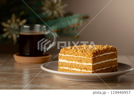 Layered honey cake on a background of Christmas tree. 119940957