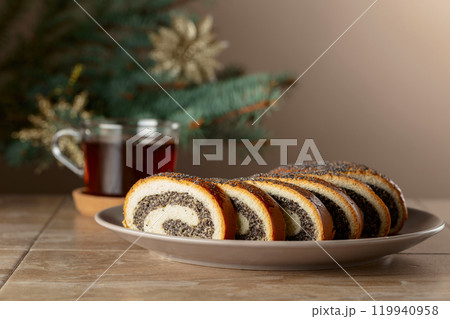 Poppy seed roll pieces on a background of Christmas tree. 119940958