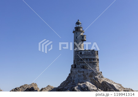 Aniva - The abandoned lighthouse in the Sakhalin Island, Korsakov district, Russia. Pacific ocean. The abandoned lighthouse Island Blue sea. Beautiful view. Blue sky and blue Pacific ocean. 119941314