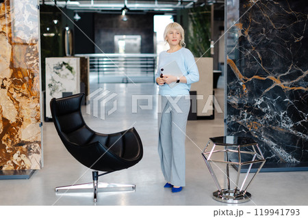 Confident Businesswoman Holding Tablet in Modern Office Setting Confident Businesswoman Holding Tablet in Modern Office Setting 119941793