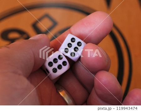 A hand shows two six-sided dice with black dots A hand shows two six-sided dice with black dots 119943474