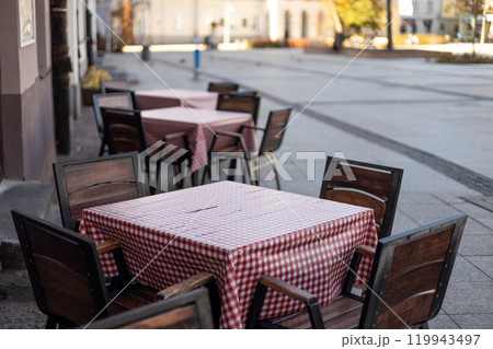 Outdoor street cafe tables ready for service. Empty cafe terrace with table and chair, morning time. Food concept Outdoor street cafe tables ready for service. Empty cafe terrace with table and chair, morning time. Food concept 119943497