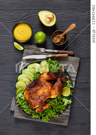 whole roasted chicken with avocado, lime on plate 119945462